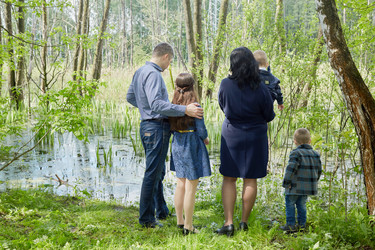 Family of five stands on boggy pond shore in - paha_l