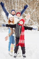 Smiling family of four stands on skates on ice - paha_l