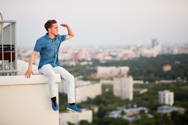 Young man in denim clothes looks afar, sitting on - paha_l