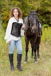 Woman with curly hair stands with bay horse in the - paha_l