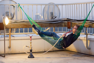 Young man lies in hammock and smokes hookah on - paha_l