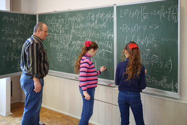 Teacher and two girls stand near blackboard with - paha_l