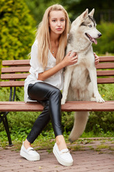 Young blond woman with dog Husky sits on bench in - paha_l