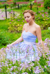 Pretty woman in long blue dress poses near flowers - paha_l