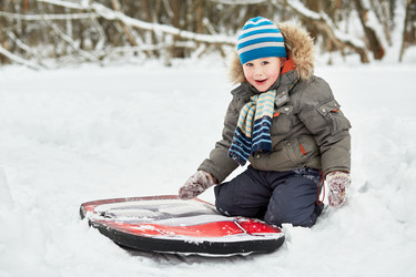 Little boy sits on snow near soft sledges in - paha_l