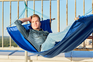 Young man in denim clothes lies in hammock mounted - paha_l