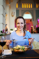 Pretty curly woman in blue dress eats salad in - paha_l