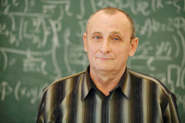 Old teacher stands near blackboard in classroom, - paha_l