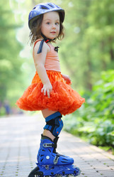 Little girl in skirt and helmet roller skates in - paha_l