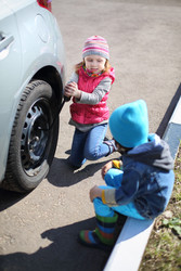 Little girl with boy tie rear wheel of car with - paha_l