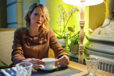 Middleaged pretty woman sits with tea and looks at - paha_l
