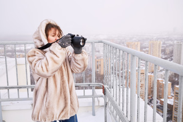 женщина в меховой куртке фотографирует город - paha_l
