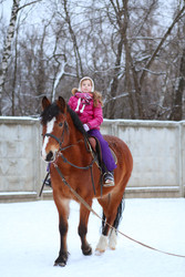 Little girl in winter clothes sitting on horseback - paha_l