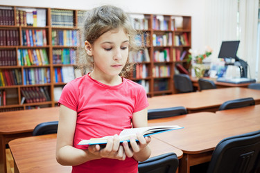 Little girl stands reading book in the hall of - paha_l