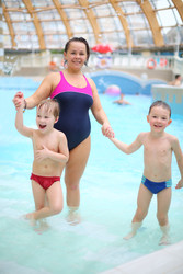 Woman with two happy little boys in a pool at a - paha_l