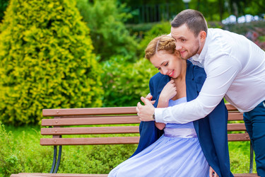 женщина сидит на скамейке, мужчина надевает свою куртку для девушки - paha_l