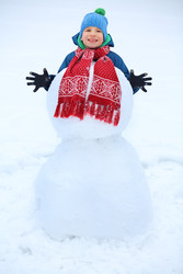 Boy plays with snowman - with red scarf during - paha_l