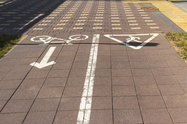 • Bicycle and pedestrian paths with white painted signs on cobblestone pavement. Outdoors - Pazemin