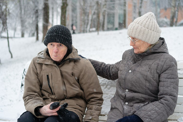 пожилая женщина трогает мужчину за плечо на заснеженной скамейке зимой - ElenaSk