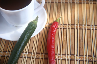 Белая чашка черного кофе с зернами, палочками корицы и шоколадными печеньями на столе - ZemLenik_photoclb