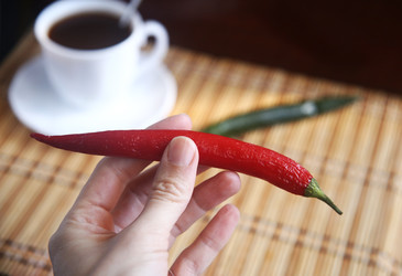 Белая чашка черного кофе и женская рука с красным и зеленым острым перцем чили - ZemLenik_photoclb