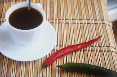 Белая чашка черного кофе с зеленым и красным острыми перцами чили на бамбуковом коврике - ZemLenik_photoclb