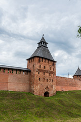 великий новгород, россия. спасская башня новгородского кремля, крепостные стены из красного кирпича и крутая шатровая крыша, вид под низким углом на средневековую архитектуру под облачным летним небом - NikitaMaykov