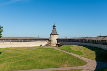 псков, россия. башня кутекрома псковского кремля, круглая белокаменная крепостная башня с крутой деревянной крышей и сторожевой башенкой, панорамный летний вид под ясным голубым небом - NikitaMaykov