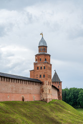 великий новгород, россия. башня кокуй новгородского кремля со стенами из красного кирпича, высокой шатровой крышей, крепостной архитектурой и вертикальными средневековыми формами под пасмурным летним небом - NikitaMaykov