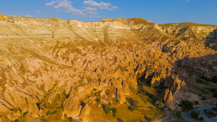 гереме, невшехир, турция. сказочные дымоходы каппадокии и разрушенные вершины из вулканического туфа, сияющие в теплом золотистом свете, открывают вид с беспилотника на обширную скалистую долину. - NikitaMaykov