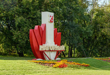 москва, россия - 25.09.2026: стальной памятник в нагорном районе, московский парк с красными скульптурными формами, яркими цветами и зеленью - Sadoff