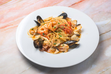 вкуснейшая итальянская паста с морепродуктами подается на белой тарелке - Carlos l vives