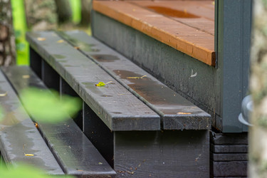 мокрые деревянные ступени с опавшими желтыми листьями на темно-серых досках и коричневое крыльцо, деталь наружной архитектуры - lidalnk