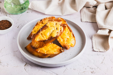 пшеничные гренки с пармезаном, растопленные в духовке, на тарелке на столе - Elena Rui