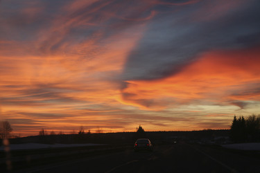 Драматичный закат над шоссе с машиной и силуэтами деревьев. Dramatic sunset over a highway with a car and silhouettes of trees - Karagero