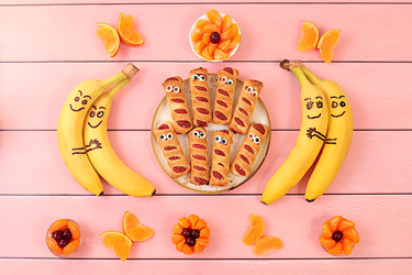 забавное песочное печенье в форме мумии с вишневой начинкой и леденцовыми глазками в сопровождении мандариновых бабочек, цветов и влюбленных бананов. игривое угощение для детей и креативная идея подачи для вечеринок - svetlanabalyn