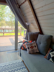 Интерьер glamping pod, гостиная в каркасном домике с диваном и подушками, внутри никого - EvgenyHaritonov
