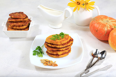 натуральная веганская еда.вкусные вегетарианские блинчики в русском стиле, блинчики с тыквой, тыквенными семечками и петрушкой, подаются с порцией сметаны на кухонном столе, концепция здорового питания, - svetlanabalyn