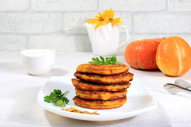 вкусные вегетарианские блинчики в русском стиле, блинчики с тыквой, тыквенными семечками и петрушкой, подаются с порцией сметаны на кухонном столе - концепция здорового, диетического питания - svetlanabalyn