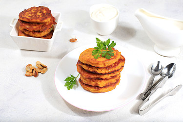 вкусные вегетарианские блинчики в русском стиле, блинчики с тыквой, тыквенными семечками и петрушкой, подаются с порцией сметаны на кухонном столе - концепция здорового, диетического питания - svetlanabalyn