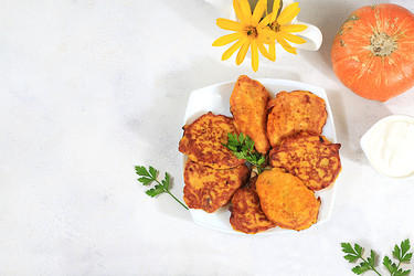 вкусные вегетарианские блинчики в русском стиле, блинчики с тыквой, тыквенными семечками и петрушкой, подаются с порцией сметаны на кухонном столе - концепция здорового, диетического питания - svetlanabalyn
