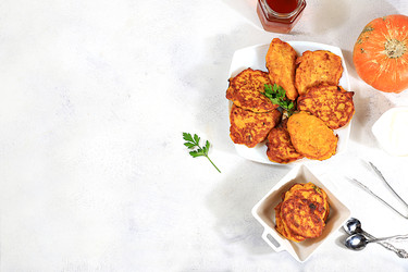 вкусные вегетарианские блинчики в русском стиле, блинчики с тыквой, тыквенными семечками и петрушкой, подаются с порцией сметаны на кухонном столе - концепция здорового, диетического питания - svetlanabalyn