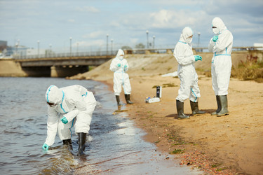 Экологи в защитных костюмах собирают пробы воды для проверки на загрязнение - DragonImagesAsia