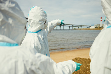 Экологи в защитных костюмах проверяют загрязнение воды на открытом воздухе - DragonImagesAsia