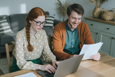 Мужчина и женщина работают дома за ноутбуком с документами - SeventyFour