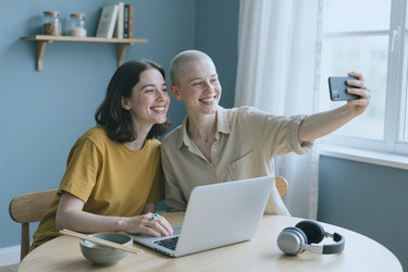 Two Happy Women Taking Selfie on Smartphone near Laptop at Home - AnnaStills